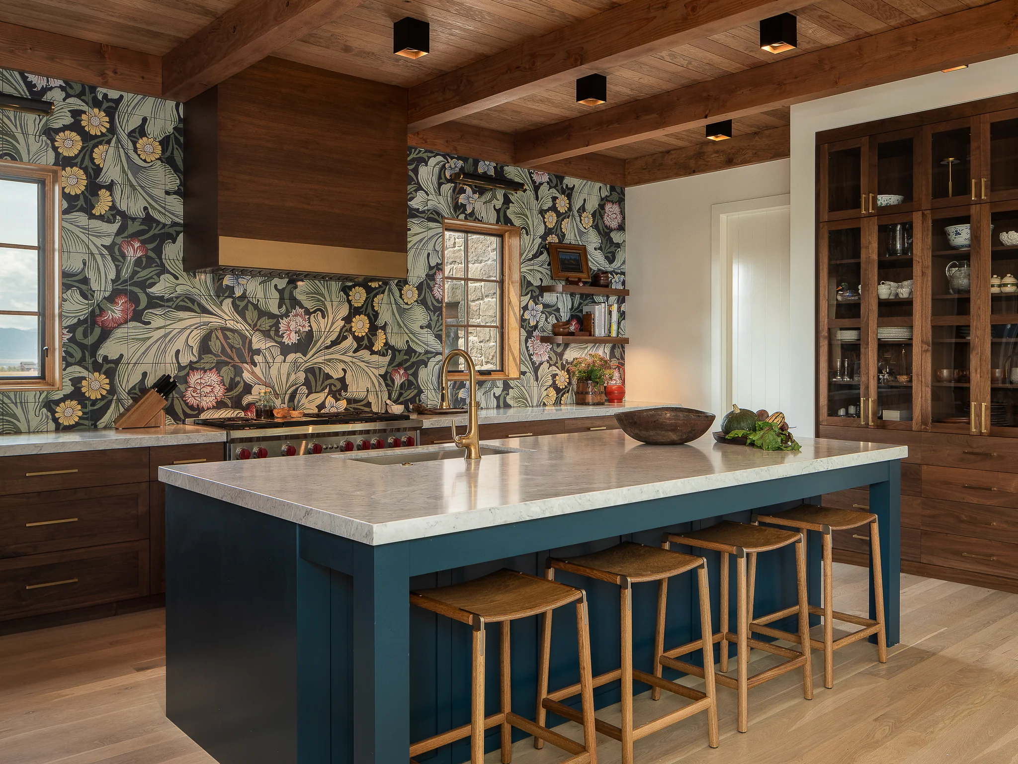 Kitchen with William Morris floral wallpaper, a blue island, and walnut cabinetry — interior design photography Driggs Idaho, WTG Architects